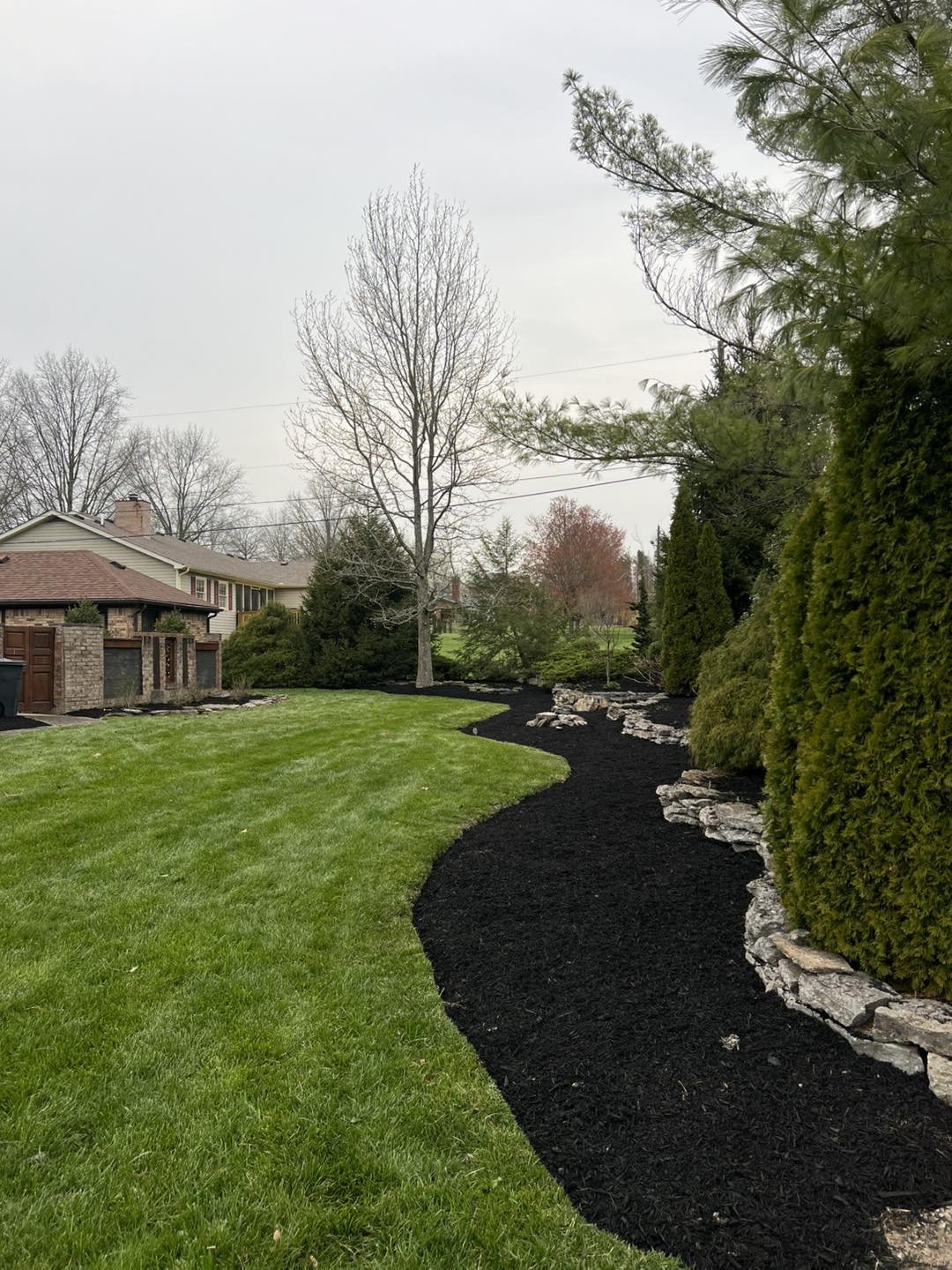 A meticulously edged mulch bed transitioning into a freshly striped lawn