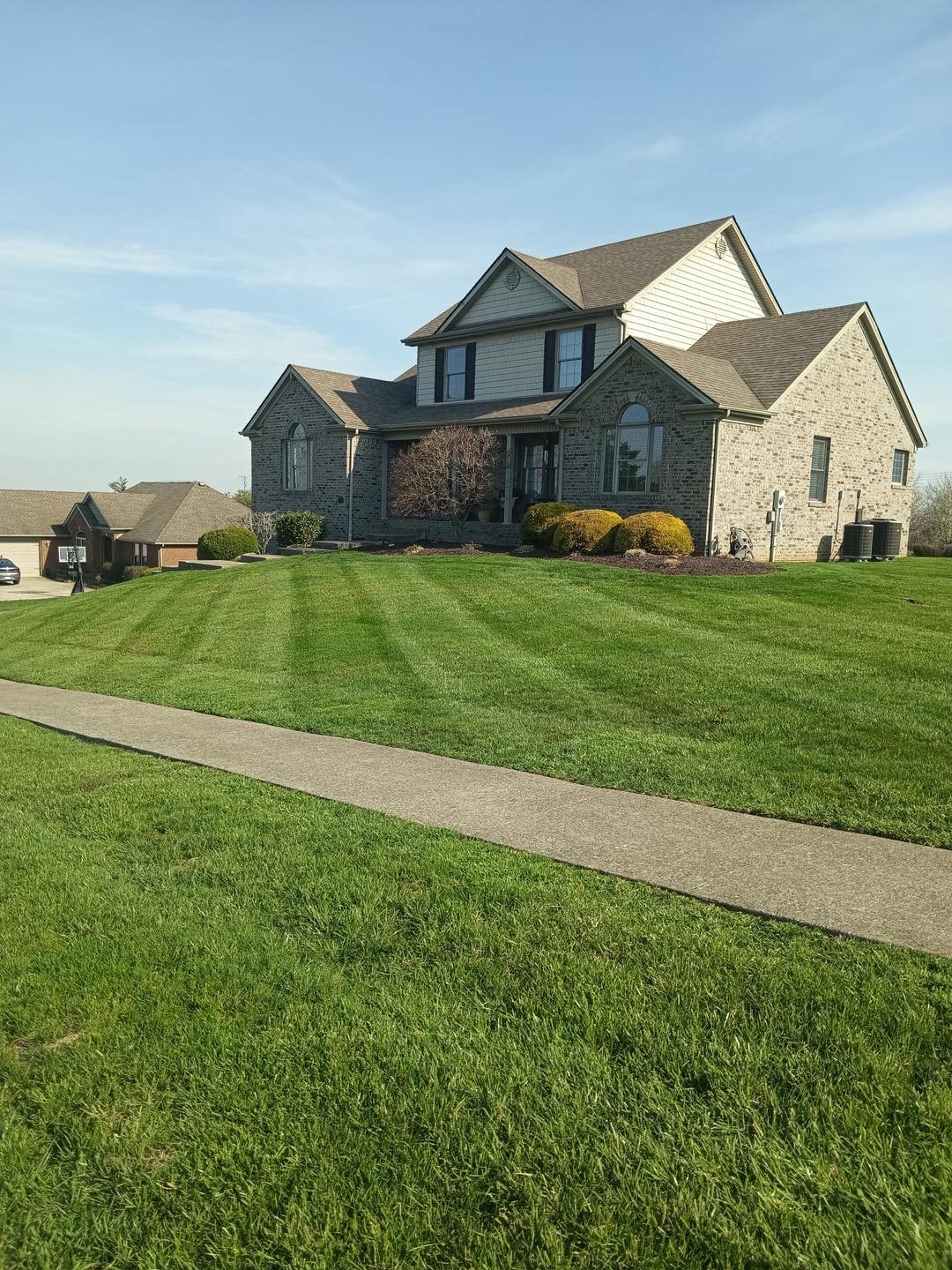 A freshly mowed striped lawn in front of a brick home